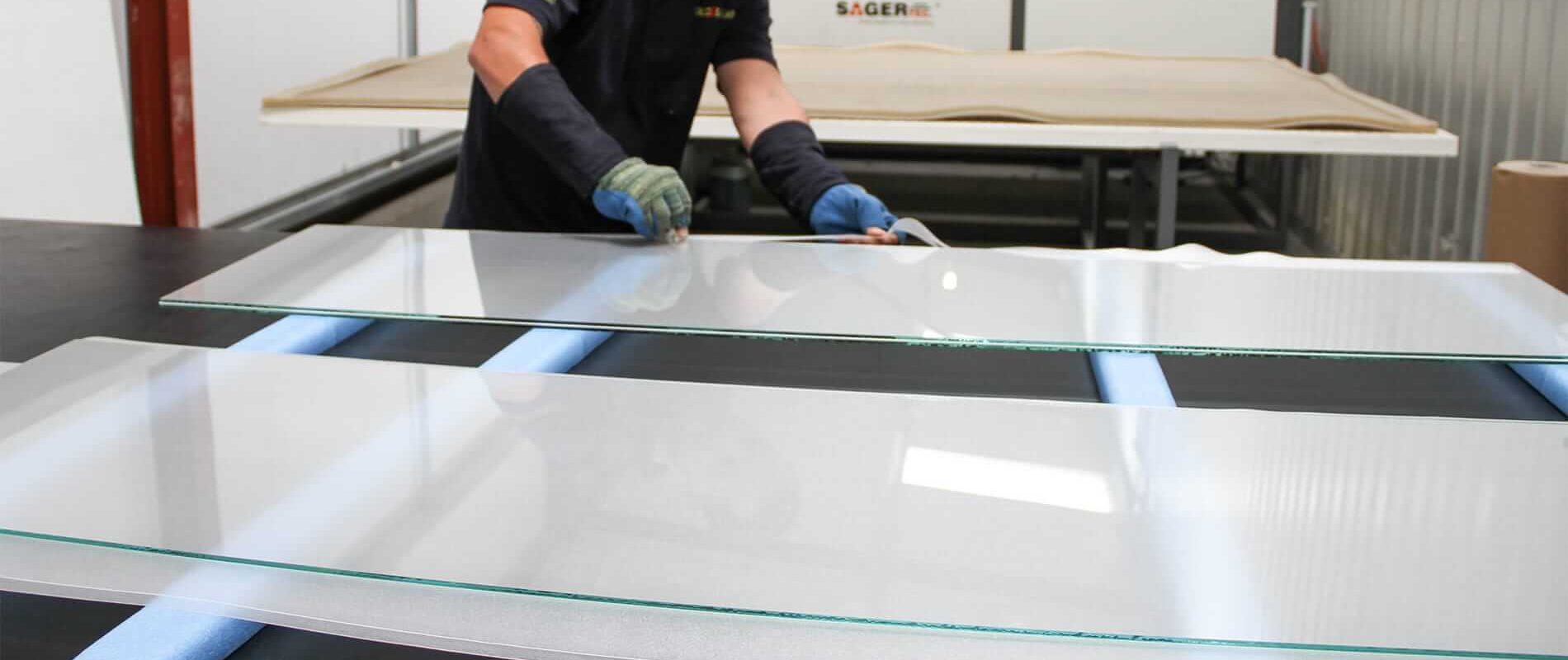 Worker cutting laminate at the edges of glass